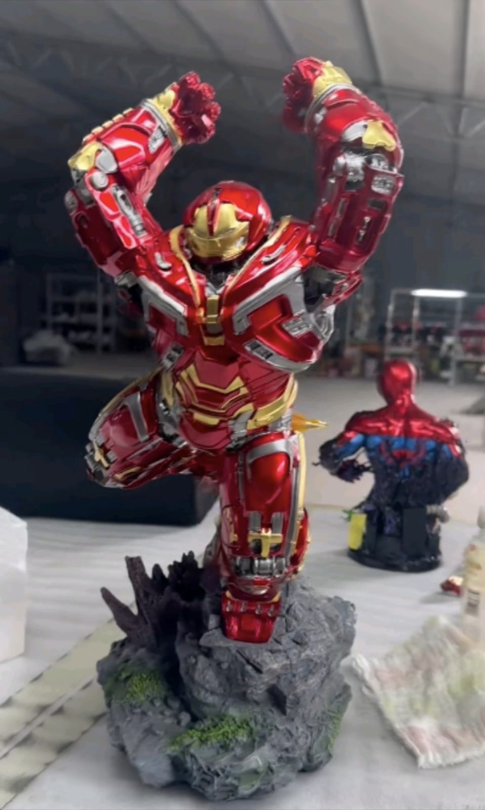 Red and gold Hulkbuster-style Iron Man collectible statue on a rocky display base